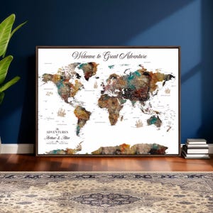 May include: A framed world map with a brown wooden frame. The map features a watercolor design with shades of brown, green, and blue. The text "Welcome to Great Adventure" is at the top, and "The Adventures of Arthur & Alice" is at the bottom.