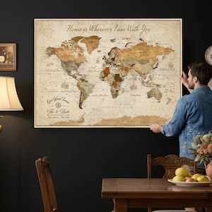 May include: A framed world map with a vintage aesthetic. The map features a sepia-toned color palette with detailed geographical features. Text on the map reads "Home is Wherever I am With You" and "Our World Travels Tim & Beth".