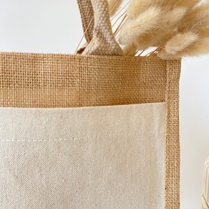 May include: A brown burlap tote bag with a white cotton bottom. The bag has a single handle and is made of natural materials.