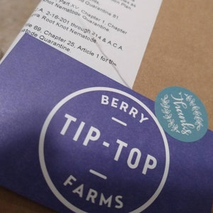 May include: A purple sticker with white text that reads "Berry Tip-Top Farms" in a circle. A teal sticker with white text that reads "Thanks" in a circle with a wreath design is on top of the purple sticker.