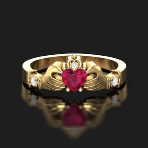 May include: A gold ring featuring a red heart-shaped gemstone and two smaller diamonds on either side. The ring is crafted in a Celtic knot design.