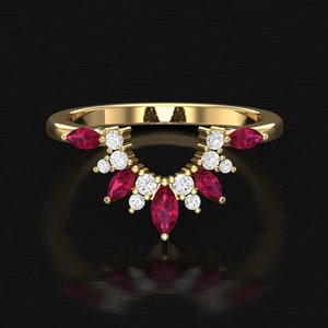 May include: A gold ring with a fan-shaped design. The ring features marquise-cut ruby gemstones and round white diamonds. The gemstones are set in a delicate, curved arrangement, creating a sparkling and elegant look.