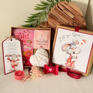 Könnte beinhalten: Drei Keramikbecher mit cremefarbener, gesprenkelter Glasur. Jeder Becher zeigt ein handgemaltes Blumenmuster in Blau-, Grün- und Gelbtönen. Die Becher haben eine einfache, abgerundete Form und einen Henkel.