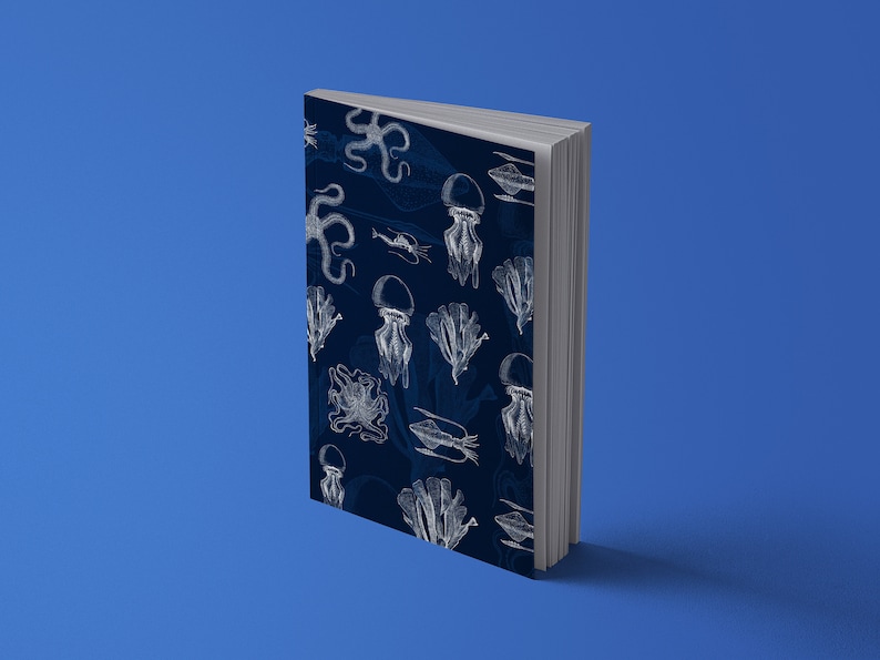 K&ouml;nnte beinhalten: Ein Hardcover-Buch mit marineblauem Einband, verziert mit wei&szlig;en Illustrationen von Meereslebewesen wie Quallen und Tintenfischen. Das Buch steht vor einem einfarbigen blauen Hintergrund.