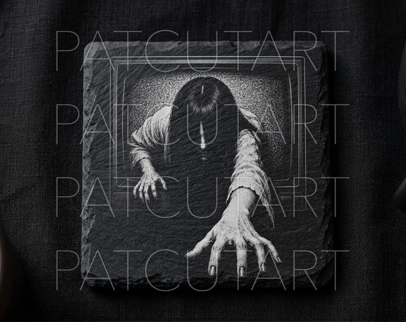 May include: A square black slate coaster featuring a detailed white engraved illustration of a long-haired figure emerging from a television screen with a hand reaching forward. The surface has a rough, natural stone texture with visible edges.