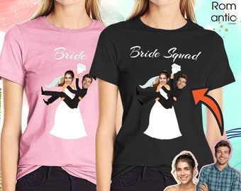 Könnte beinhalten: Zwei T-Shirts, eines rosa und eines schwarz, mit einem Motiv, das eine Braut zeigt, die von einem Bräutigam getragen wird. Der Text auf dem rosa T-Shirt lautet "Bride" und der Text auf dem schwarzen T-Shirt lautet "Bride Squad".