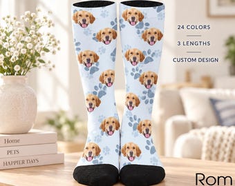 Könnte beinhalten: Ein Paar hellblaue Socken mit einem wiederkehrenden Muster aus Golden Retriever-Gesichtern und grauen Pfotenabdrücken. Die Socken haben schwarze Zehen- und Fersenbereiche. Der Text lautet CUSTOM PET SOCKS, 24 COLORS, 3 LENGTHS, CUSTOM DESIGN, 30 cm, 40 cm, 46 cm.