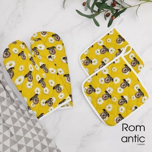 May include: Yellow oven mitts and pot holders with a daisy and dog face pattern. The set includes two pot holders and one pair of oven mitts. The word "Romantic" is printed on the bottom right corner.