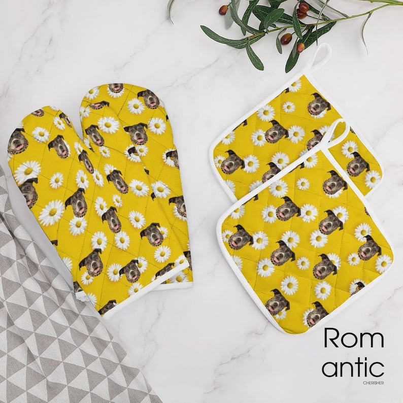 May include: Yellow oven mitts and pot holders with a daisy and dog face pattern. The set includes two pot holders and one pair of oven mitts. The word "Romantic" is printed on the bottom right corner.