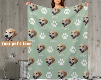 May include: A green fleece blanket with a repeating pattern of a dog's face and paw prints. The dog's name "HANK" is printed on the blanket.