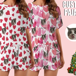 Puede incluir: Un pijama blanco de manga corta y pantalón corto con un estampado de corazones rojos y caras de gato. El texto "CUSTOM PAJAMS" es visible en la esquina superior derecha de la imagen.