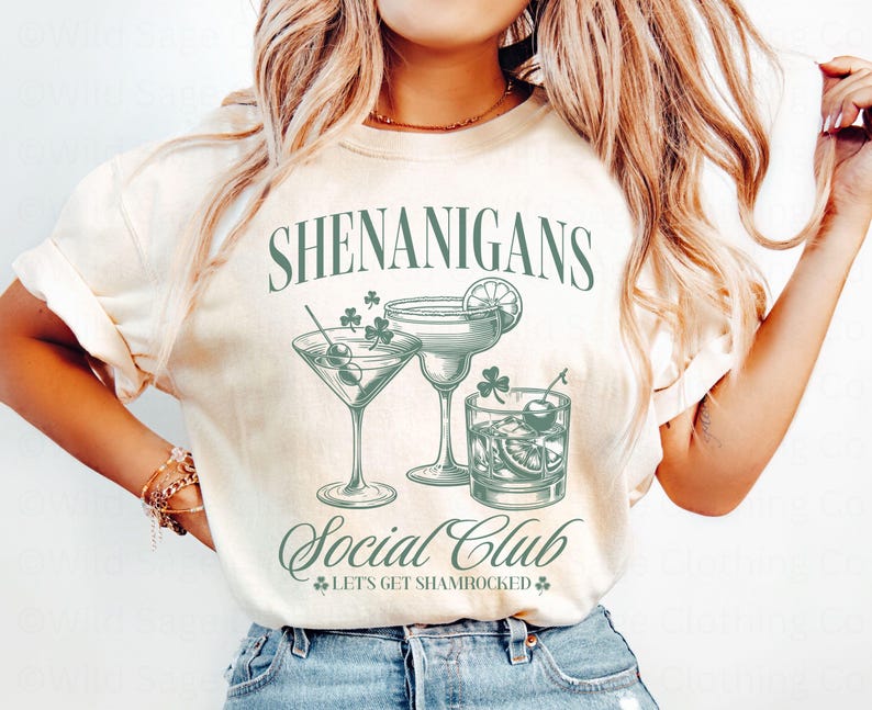 May include: A white t-shirt with the text "Shenanigans Social Club - Let's Get Shamrocked" in green lettering. The shirt features a graphic of three cocktail glasses with green shamrocks and a lime wedge.