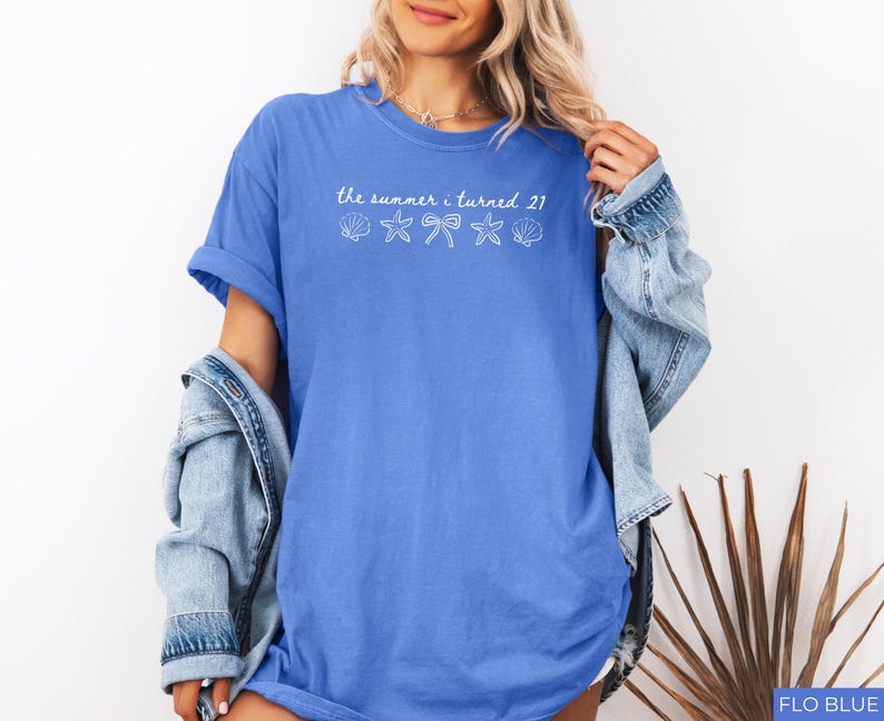 Pu&ograve; includere: Una maglietta blu con la scritta "the summer i turned 21" e grafiche di conchiglie, stelle marine e fiocchi. La maglietta &egrave; di colore blu unito e ha maniche corte. Una giacca di jeans &egrave; drappeggiata sulle spalle.