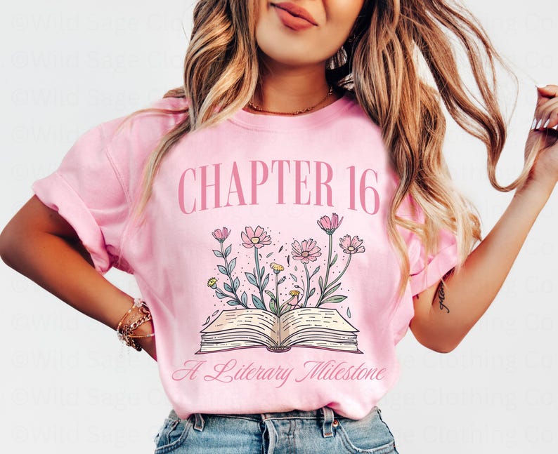 Puede incluir: Camiseta rosa con el texto "Cap&iacute;tulo 16 Un Hito Literario" y un dibujo de un libro abierto con flores.