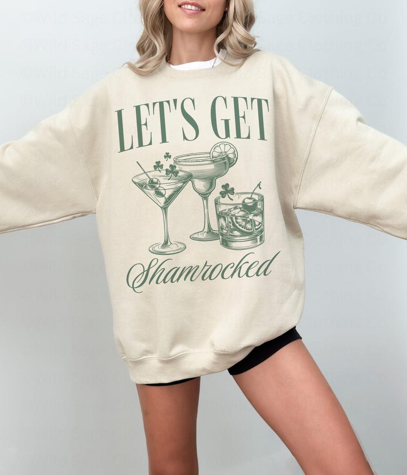 May include: A beige sweatshirt with the text "Let's Get Shamrocked" and a graphic of three cocktail glasses with shamrocks.