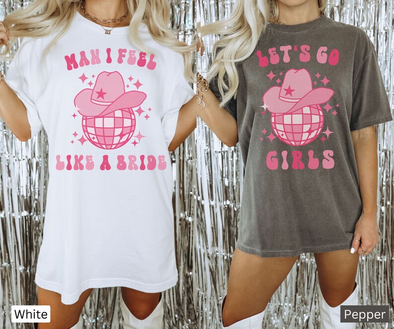 K&ouml;nnte beinhalten: Zwei wei&szlig;e T-Shirts mit pinkfarbenen Grafiken. Das linke Shirt sagt "Man I feel like a bride" mit einer pinkfarbenen Discokugel und einem Cowboyhut. Das rechte Shirt sagt "Let's go girls" mit einer pinkfarbenen Discokugel und einem Cowboyhut.