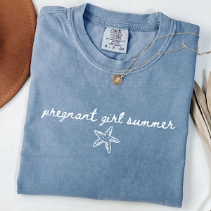May include: A light blue t-shirt with the text "pregnant girl summer" and a white starfish graphic.