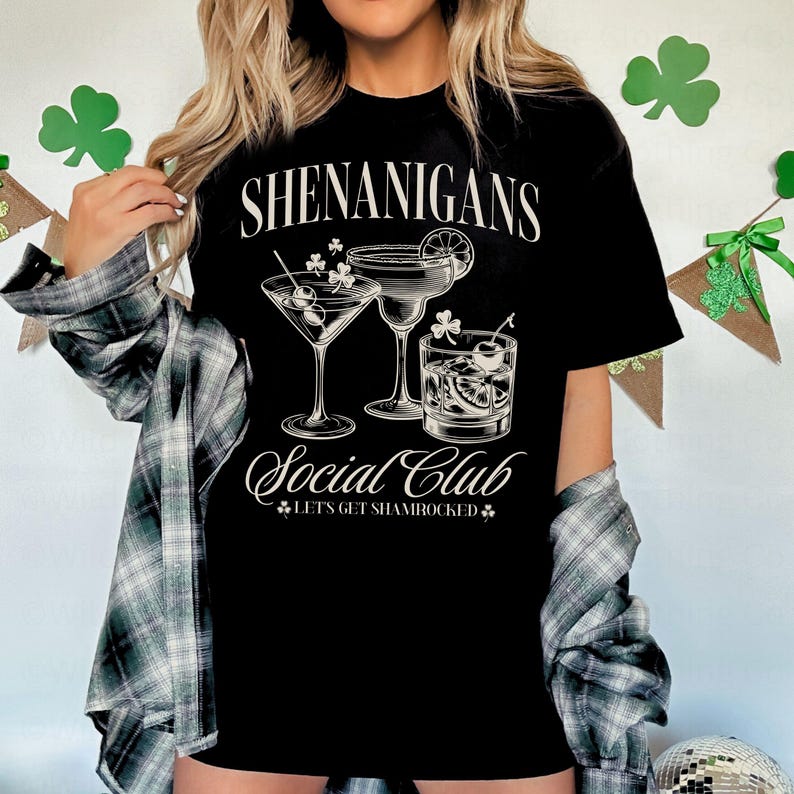 May include: Black t-shirt with white text that reads "Shenanigans Social Club Let's Get Shamrocked" and a graphic of three cocktails.