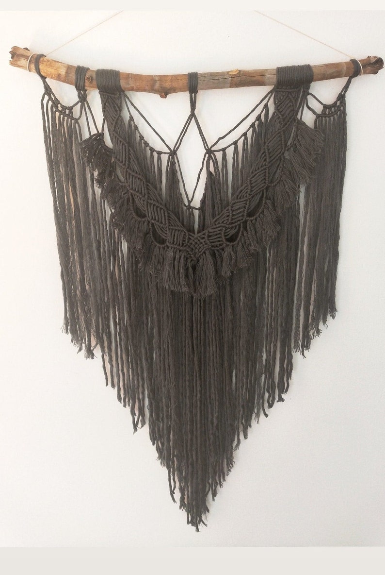 May include: A gray macrame wall hanging with a wooden branch at the top and long fringe tassels.