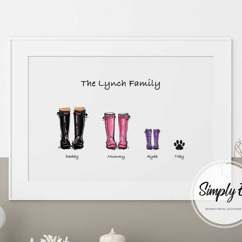 May include: A white framed print with the text "The Lynch Family" at the top.  Below the text are four pairs of rain boots, two black, two pink, and two purple.  Each pair of boots is labelled with a name: "Daddy", "Mummy", "Ayda", and "Toby".  A paw print is below the purple boots.