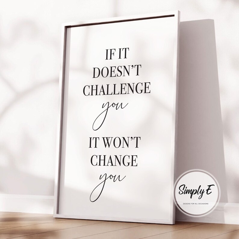 Może przedstawiać: Biała oprawiona grafika z cytatem "If it doesn't challenge you, it won't change you" czcionką w kolorze czarnym. Grafika opiera się o ścianę. Okrągłe logo z napisem "Simply E" znajduje się w prawym dolnym rogu.