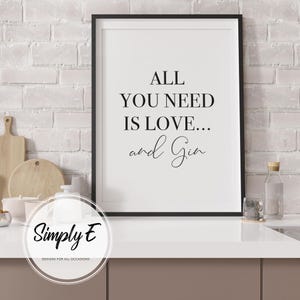 Peut inclure: Tableau encadr&eacute; noir avec le texte "ALL YOU NEED IS LOVE... and Gin" dans une police moderne. L'impression est affich&eacute;e sur un comptoir blanc avec un fond de mur en briques. Un article de cuisine d&eacute;coratif.