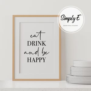 Peut inclure: Une impression encadr&eacute;e avec le texte "eat DRINK and be HAPPY" en &eacute;criture cursive noire sur fond blanc. Le cadre est en bois brun clair.