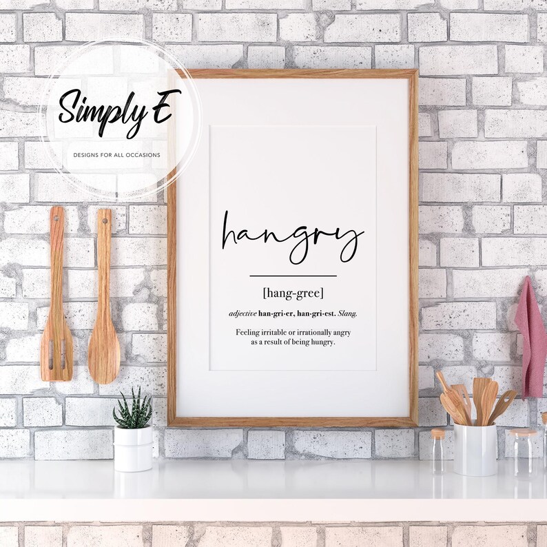 K&ouml;nnte beinhalten: Ein wei&szlig;er gerahmter Druck mit dem Wort "hangry" in schwarzer Kursivschrift. Die Definition von hangry ist darunter in schwarzer Schrift geschrieben: "[hang-gree] Adjektiv han-gri-er, han-gri-est. Slang. Sich gereizt oder irrational w&uuml;tend f&uuml;hlen, weil man hungrig ist."
