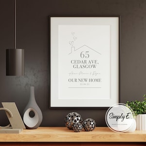 Peut inclure: Un cadre avec l'inscription "65 CEDAR AVE, GLASGOW" et "OUR NEW HOME", dans un design minimaliste. L'impression comprend un dessin de maison avec des c&oelig;urs, sur une &eacute;tag&egrave;re en bois avec des sph&egrave;res d&eacute;coratives et une plante.