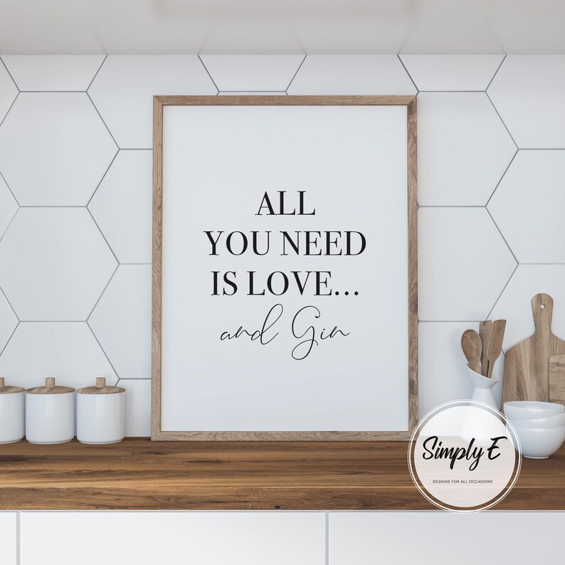 Peut inclure: Une affiche encadr&eacute;e avec le texte "ALL YOU NEED IS LOVE... and Gin" en noir. L'affiche a un cadre en bois brun clair et est affich&eacute;e sur un comptoir en bois. Des carreaux hexagonaux blancs sont en arri&egrave;re-plan.