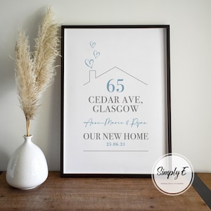 Peut inclure: Impression encadr&eacute;e avec un cadre noir. L'impression pr&eacute;sente une illustration de maison et du texte, dont l'adresse "65 Cedar Ave, Glasgow", les noms "Anne-Marie & Ryan" et "OUR NEW HOME 25.06.21". Un vase avec des plantes s&eacute;ch&eacute;es est &agrave; gauche.