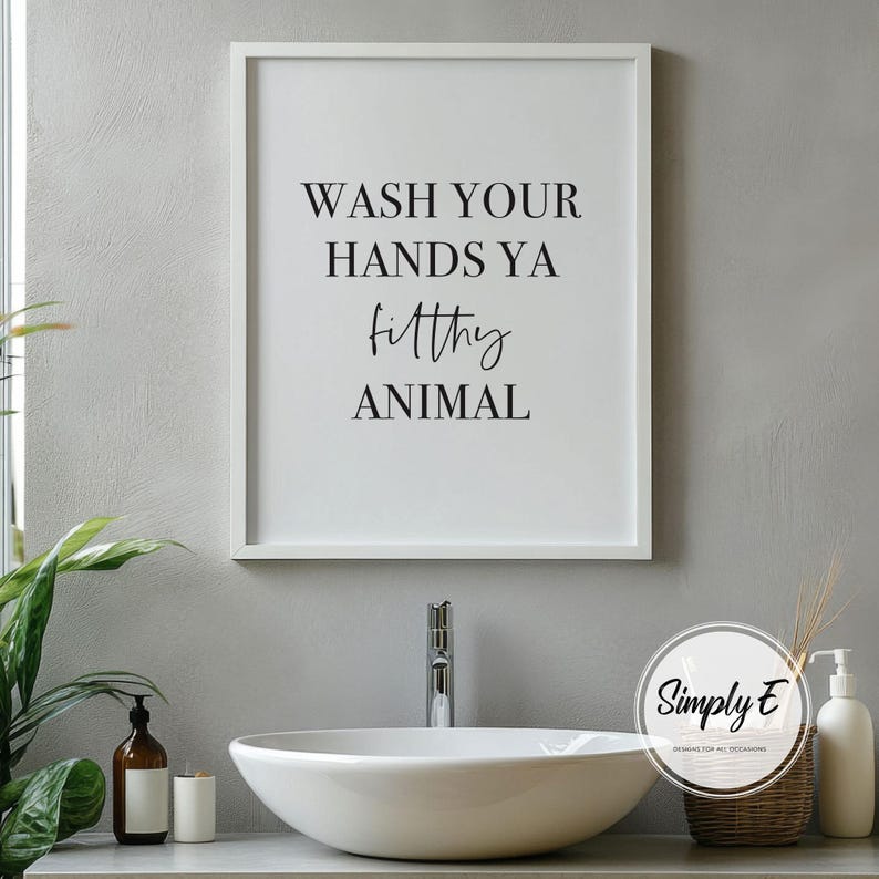 Puede incluir: Un marco blanco con el texto negro "WASH YOUR HANDS YA filthy ANIMAL". La impresi&oacute;n est&aacute; encima de un lavabo ovalado blanco, con un grifo, un dispensador de jab&oacute;n y objetos decorativos.