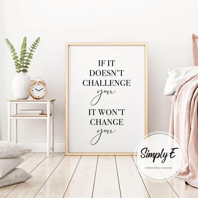 Może przedstawiać: Oprawiony wydruk z napisem "IF IT DOESN'T CHALLENGE you IT WON'T CHANGE you" czarnym skryptem. Wydruk jest w złotej ramie, eksponowany w pokoju z białą ścianą, stolikiem nocnym z wazonem i zegarem oraz ł&oacute;żkiem z r&oacute;żowym kocem.