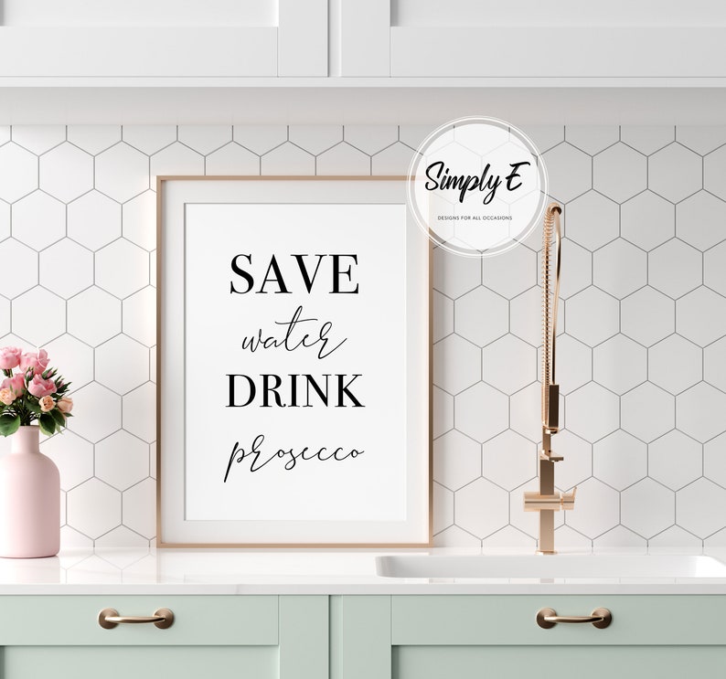 K&ouml;nnte beinhalten: Ein gerahmter Druck mit dem Text "SAVE water DRINK prosecco" in schwarzen Buchstaben auf wei&szlig;em Hintergrund. Der Rahmen ist in hellem Holz gehalten.