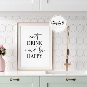 Peut inclure: Une impression encadr&eacute;e blanche avec le texte "eat DRINK and be HAPPY" en &eacute;criture cursive noire. L'impression est accroch&eacute;e &agrave; un mur blanc avec un motif de carreaux hexagonaux blancs.