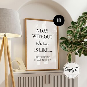 May include: A rectangular framed wall art print with a white background and black text that reads A DAY WITHOUT Wine IS LIKE... JUST KIDDING. I HAVE NO IDEA. The frame is made of light-coloured wood and is displayed in a vertical orientation.