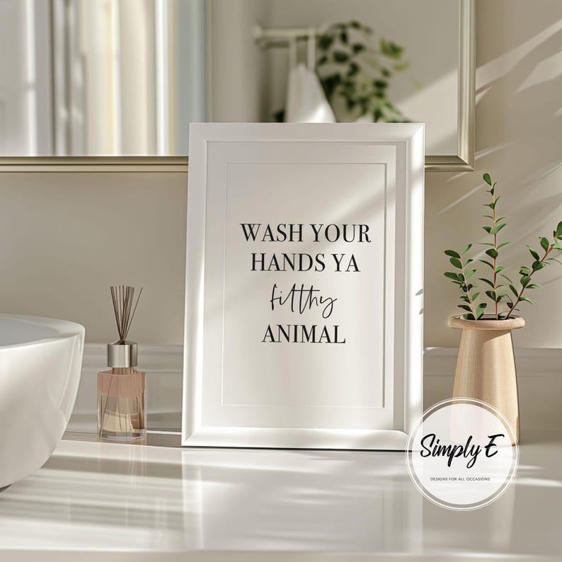 Puede incluir: Un marco blanco con el texto negro "WASH YOUR HANDS YA filthy ANIMAL". La impresi&oacute;n est&aacute; sobre una superficie blanca con un difusor, un jarr&oacute;n con vegetaci&oacute;n y un espejo en el fondo. La impresi&oacute;n es de Simply E Designs.