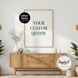 K&ouml;nnte beinhalten: Ein gerahmter Druck mit dem Text "YOUR CUSTOM QUOTE" in einer modernen Schriftart. Der Druck wird &uuml;ber einem Holzschrank mit Schubladen und dekorativen Vasen angezeigt. Das Bild enth&auml;lt den Text "other fonts available" und das Logo von "Simply E Designs for all Occasions."