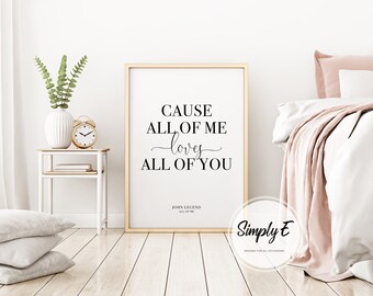 Puede incluir: Una impresión enmarcada con el texto "CAUSE ALL OF ME loves ALL OF YOU" de John Legend. La impresión está en un marco dorado y se exhibe en un dormitorio. Un jarrón blanco con vegetación y un despertador dorado están en una mesita de noche.