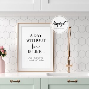 Puede incluir: Una impresi&oacute;n enmarcada con fondo blanco y texto negro que dice "A Day Without Tea Is Like... Just Kidding. I Have No Idea." La impresi&oacute;n est&aacute; colgada en una pared de azulejos blancos sobre un armario verde claro.