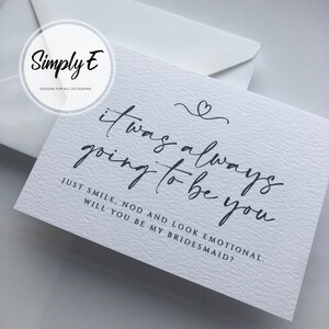 May include: A white card with black calligraphy that reads "it was always going to be you" and "Just smile, nod and look emotional. Will you be my bridesmaid?"