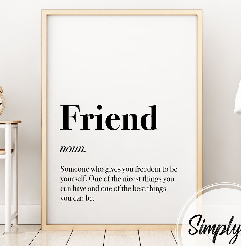 May include: A framed print featuring the word "Friend" in a bold, black font, with its definition below. The frame is a light gold colour. The background is white.