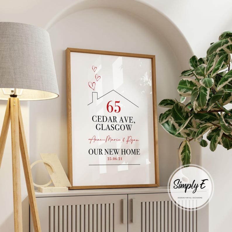 Peut inclure: Impression encadr&eacute;e avec un cadre en bois. L'impression pr&eacute;sente un dessin de maison avec le num&eacute;ro 65 en rouge, l'adresse "CEDAR AVE, GLASGOW", et le texte "OUR NEW HOME" avec une date. Les noms "Anne-Marie & Ryan" sont &eacute;galement inclus.