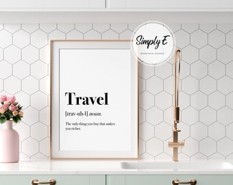 May include: A framed print with a white background and black text that reads "Travel [trav-uh-l] noun. The only thing you buy that makes you richer." The print is in a gold frame and is hanging on a white wall with a hexagonal tile pattern.