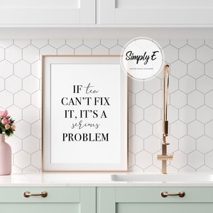 K&ouml;nnte beinhalten: Ein gerahmter Druck mit dem Text "If tea can't fix it, it's a serious problem." Der Druck h&auml;ngt an einer wei&szlig;en gekachelten Wand &uuml;ber einer hellgr&uuml;nen Arbeitsplatte.