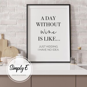 May include: Black framed print with the text "A DAY WITHOUT Wine IS LIKE... JUST KIDDING. I HAVE NO IDEA." The print is on a white background. The print is in a kitchen setting.