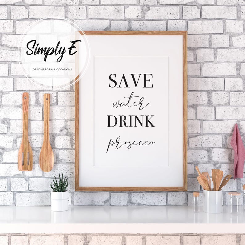 K&ouml;nnte beinhalten: Ein gerahmter Druck mit dem Text "SAVE water DRINK prosecco" in schwarzen Buchstaben auf wei&szlig;em Hintergrund. Der Druck h&auml;ngt an einer wei&szlig;en Backsteinwand.