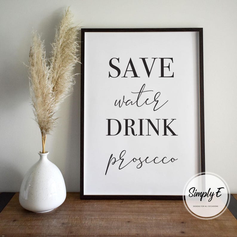 K&ouml;nnte beinhalten: Schwarz-wei&szlig;es druckbares Schild mit dem Text "Save water drink prosecco". Das Schild ist in einem schwarzen Rahmen gerahmt und liegt auf einer Holzoberfl&auml;che.