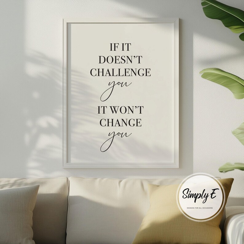 Może przedstawiać: Oprawiony wydruk z napisem "IF IT DOESN'T CHALLENGE you IT WON'T CHANGE you" czcionką w kolorze czarnym. Wydruk jest w białej ramie i wisi nad kremową sofą z ż&oacute;łtą poduszką. Logo "Simply E" znajduje się w prawym dolnym rogu.