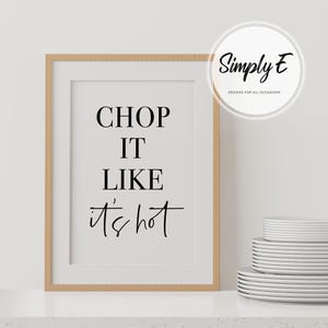 May include: A framed print with the text "CHOP IT LIKE it's hot" in black lettering on a white background. The frame is light brown wood.